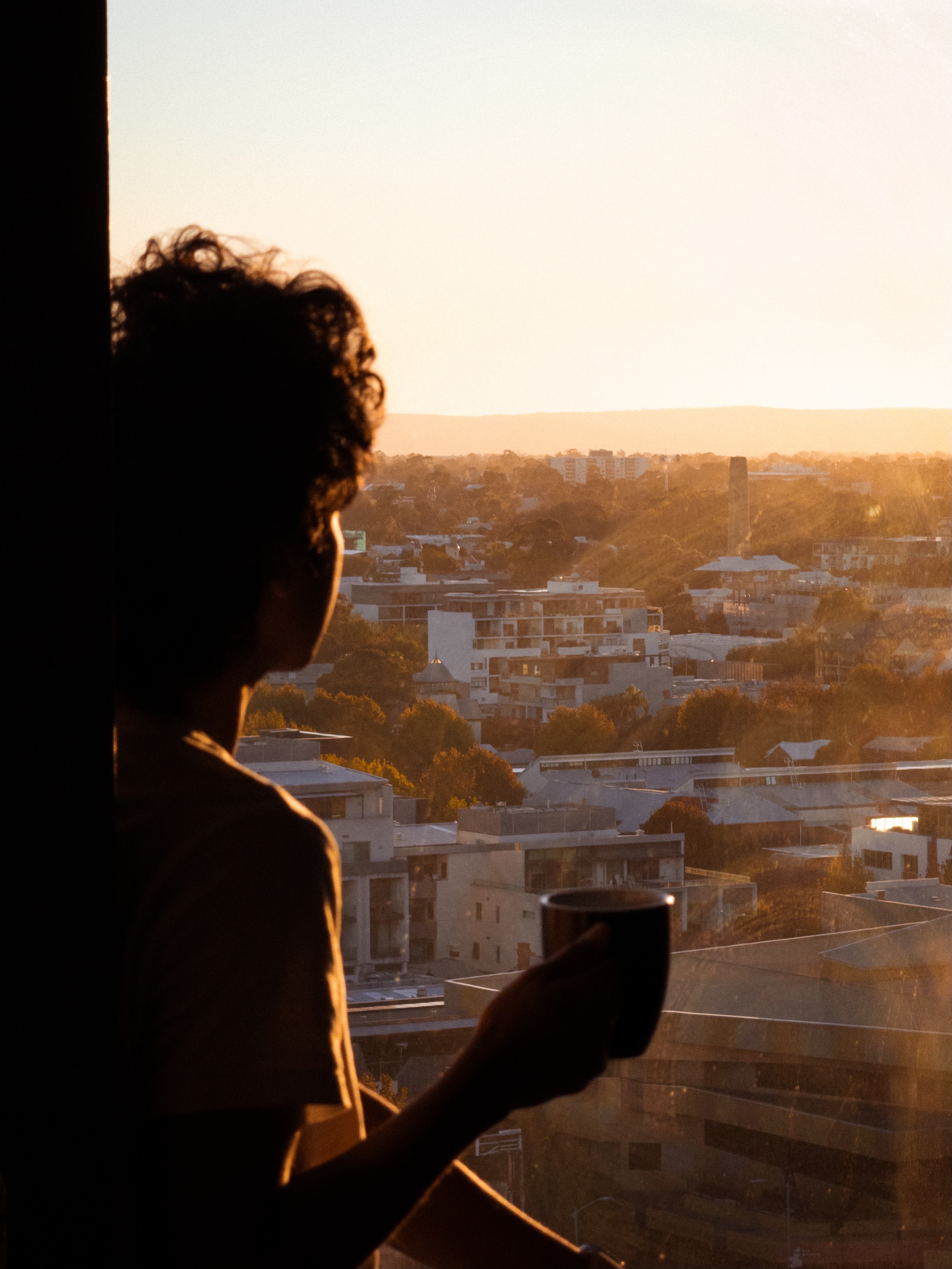 Self-portrait of Dulanga Jayawardena enjoying a morning coffee whilst overlooking the city of Perth