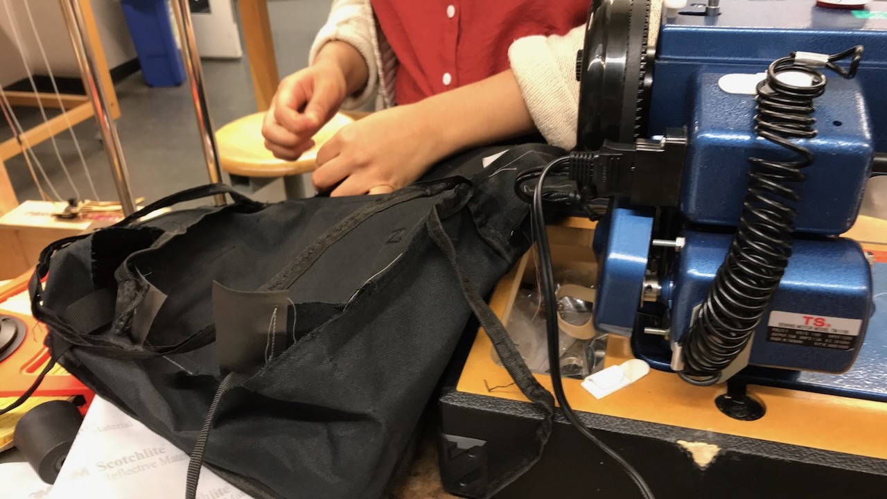 A teammate stitches together the Lit Pak backpack at the Thayer School